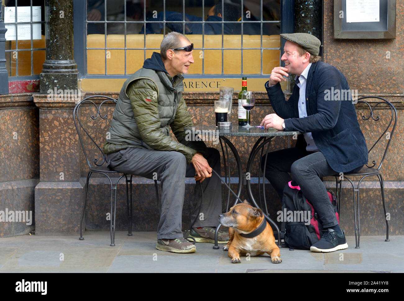 Londres, Royaume-Uni. Deux hommes et un chien à l'extérieur du pub Clarence dans Whitehall. Une consommation de bière, l'autre vin Banque D'Images