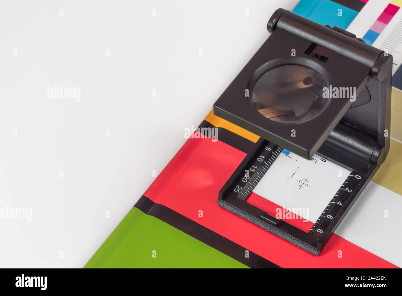 Loupe Noir debout sur l'impression test sur fond coloré. Loupe d'impression offset sur feuille imprimée avec des couleurs de base des barres de commandes. Banque D'Images