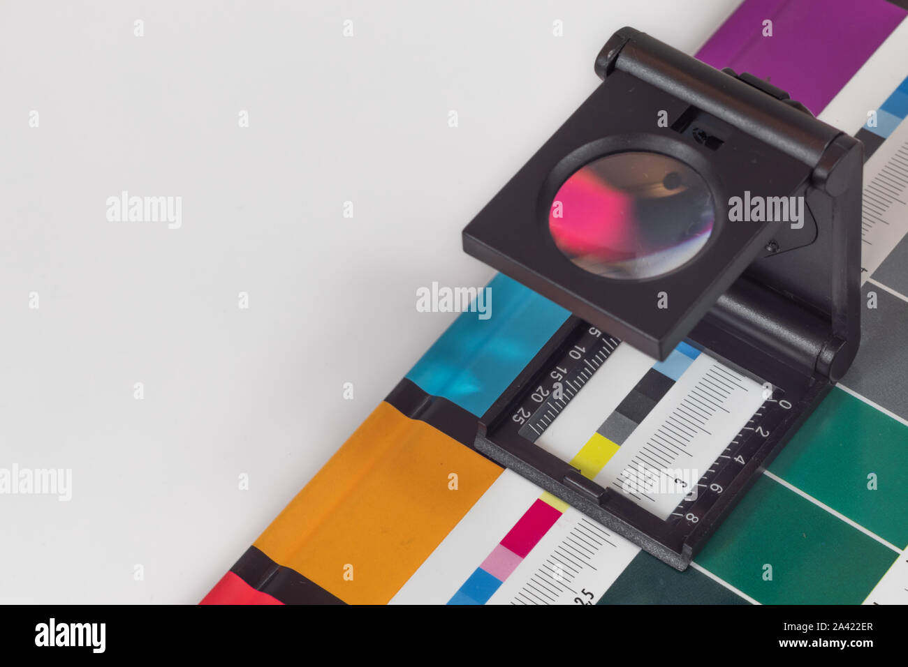 Loupe Noir debout sur l'impression test sur fond coloré. Loupe d'impression offset sur feuille imprimée avec des couleurs de base des barres de commandes. Banque D'Images