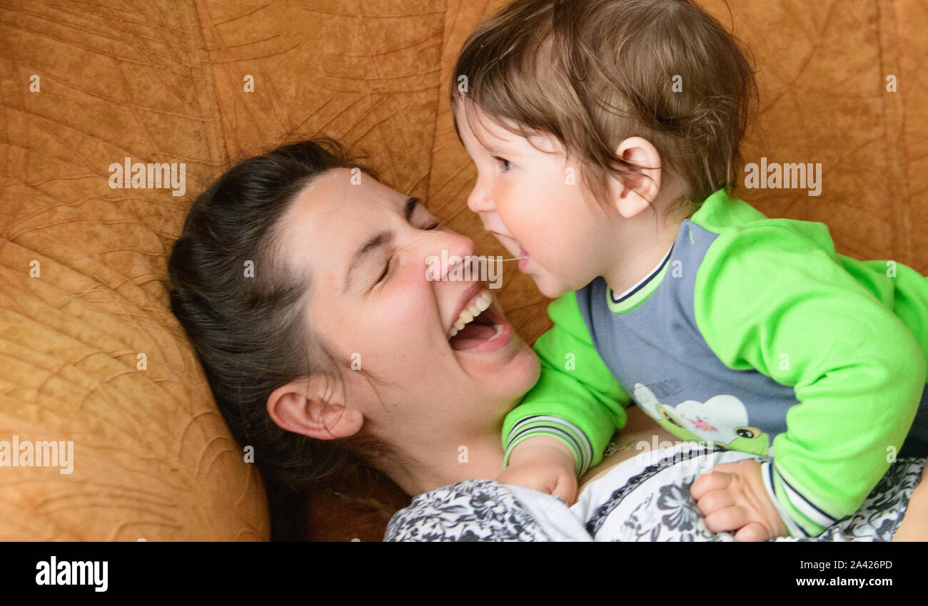 Les mamans bébé mord le nez. Happy mother with baby. Un garçon se mord la mère nez sur le canapé. avoir du plaisir avec votre Mère bien-aimée Banque D'Images