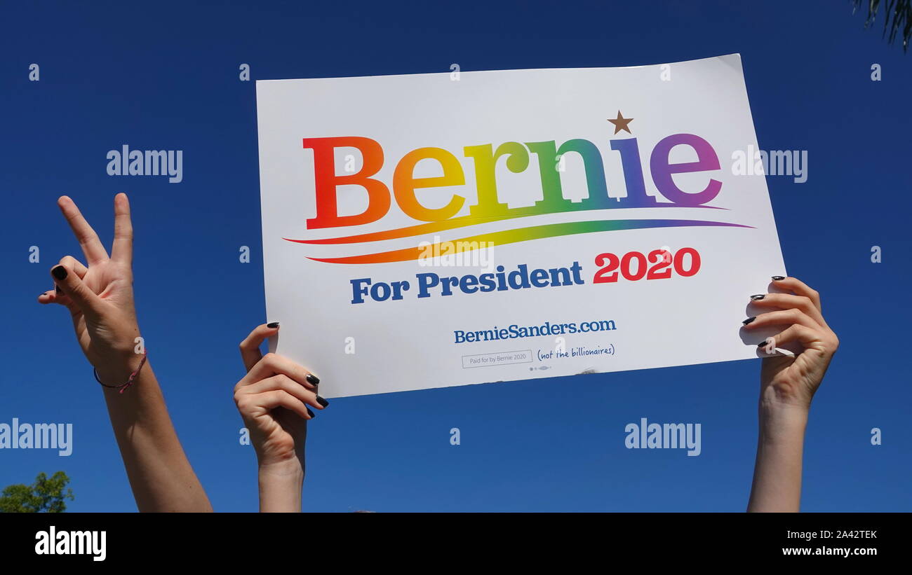 Un des ados mains tiennent une "Bernie pour le président 2020" signe dans un ciel bleu, alors qu'une autre fille clignote un signe de victoire. Banque D'Images