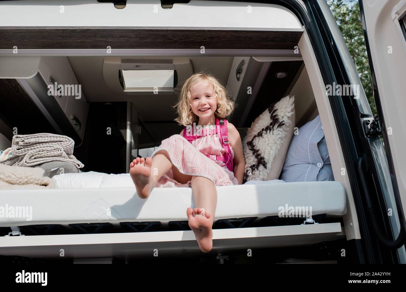 Portrait d'une jeune fille s'assit dans le lit dans un camping-car en vacances Banque D'Images