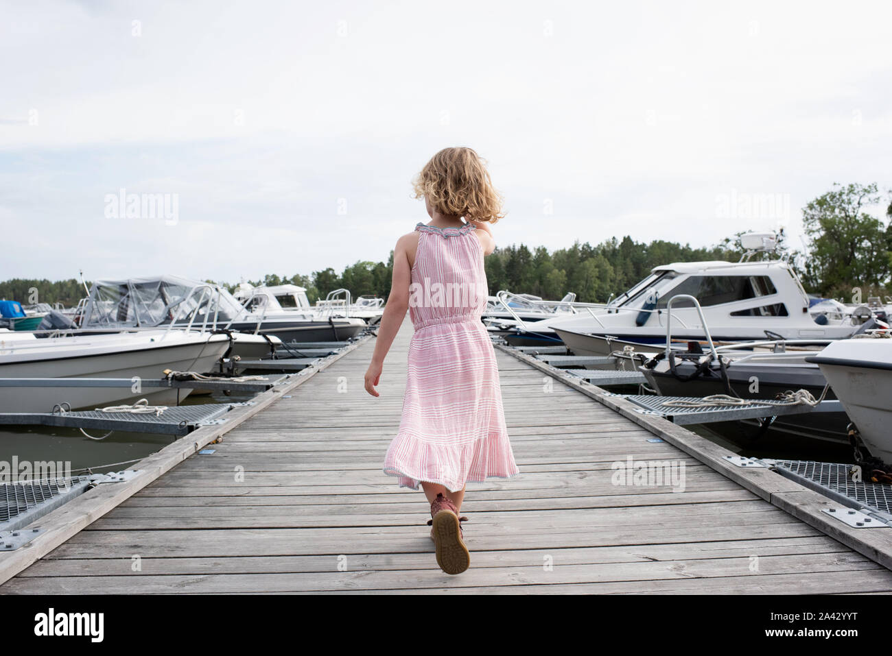 Jeune fille blonde marcher sur un quai à bateaux en mer à la Banque D'Images