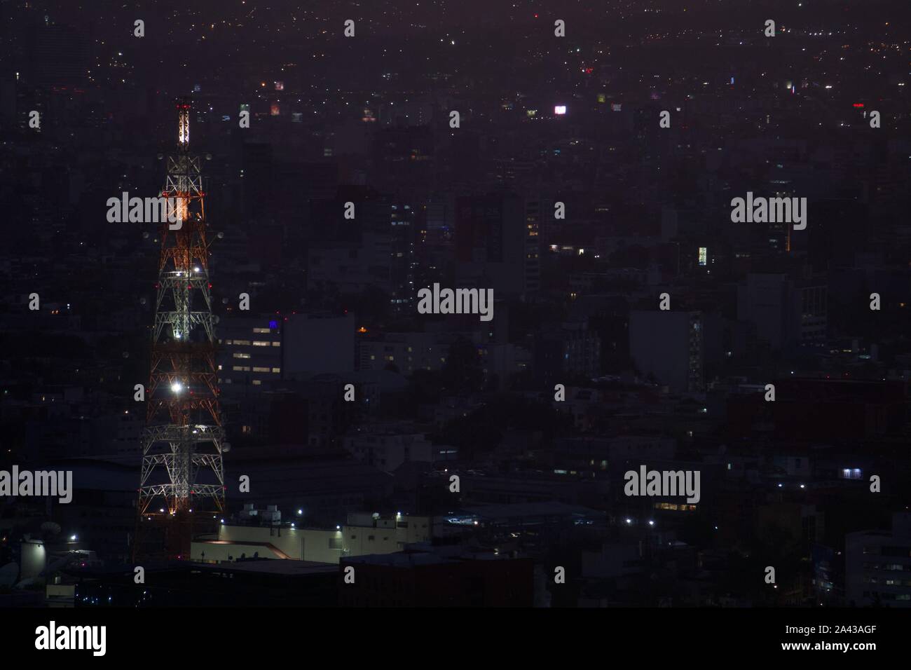 Rouge et blanc Vintage radio tower at night, soutenue par les lumières et la densité urbaine. La ville de Mexico, Mexique. Banque D'Images