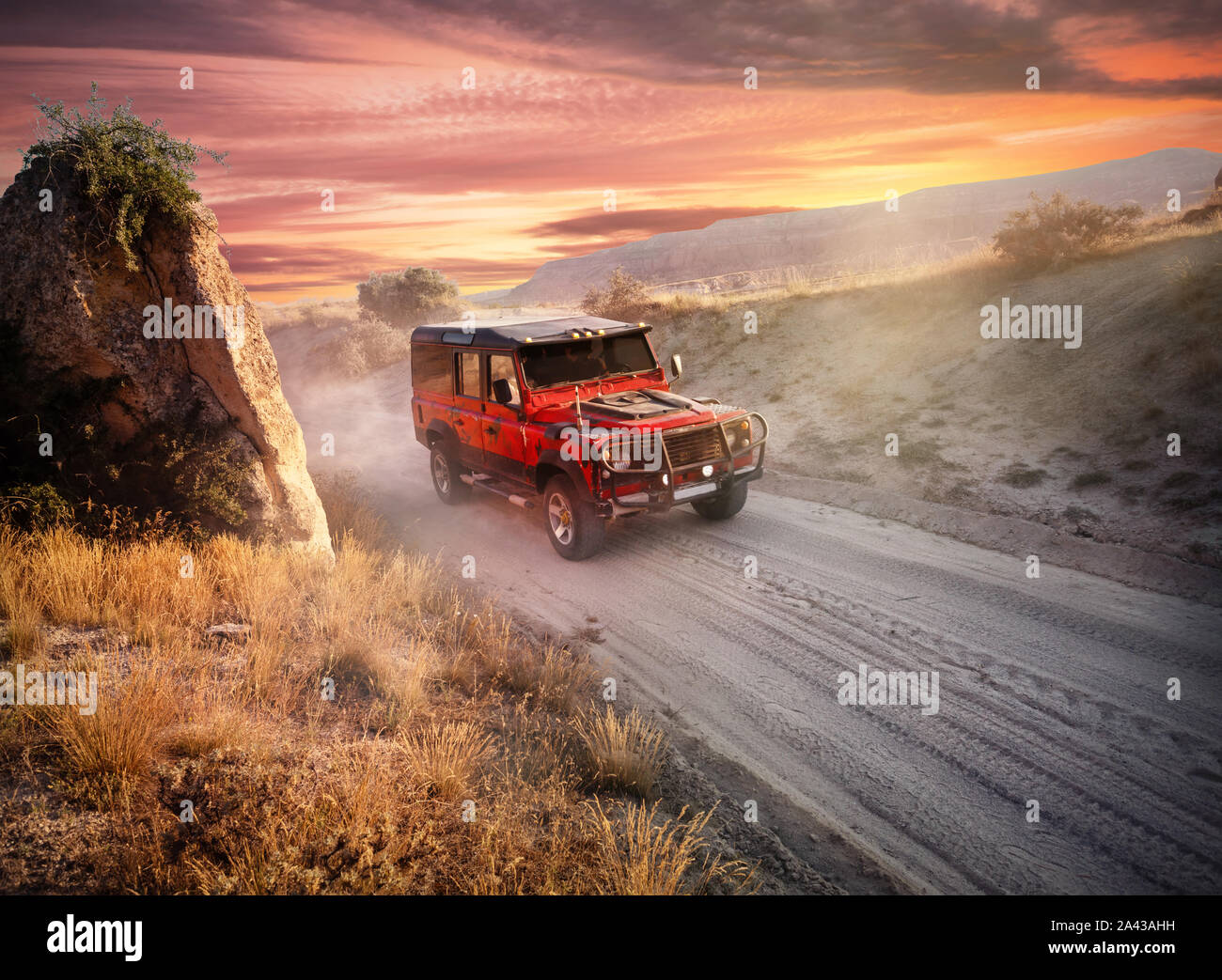 Hors-route rouge voiture sur une route poussiéreuse près de la falaise. Ciel coucher de soleil spectaculaire. La liberté et l'aventure travel concept Banque D'Images