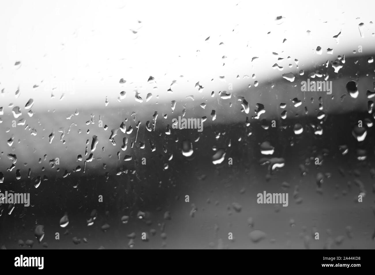 Fenêtre humide avec des gouttes de pluie. Dans brurred ciel de toit et l'arrière-plan. Temps de pluie. Bw macro image Banque D'Images