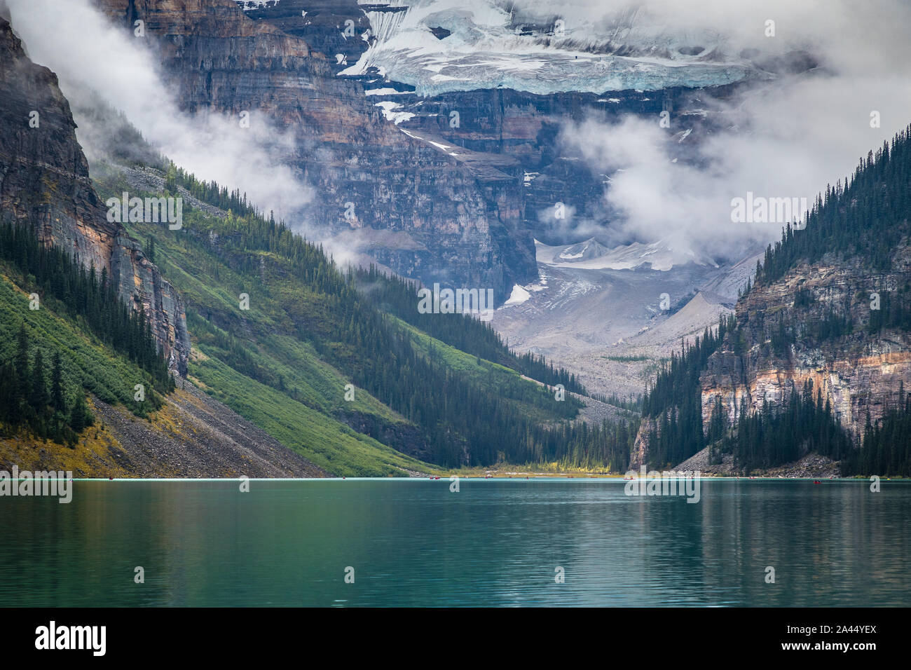 De couleur turquoise Lake Louise avec les réflexions sur les montagnes environnantes en un jour brumeux, Banff National Park, Alberta, Canada Banque D'Images