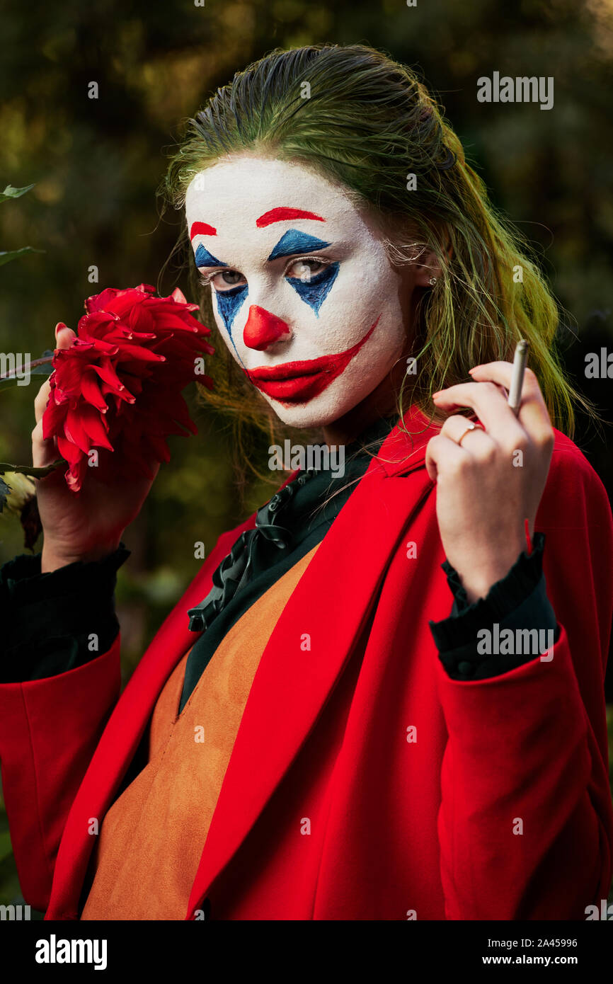 Jeune femme avec Joker costume maquillage et looking at camera, fumeurs Banque D'Images