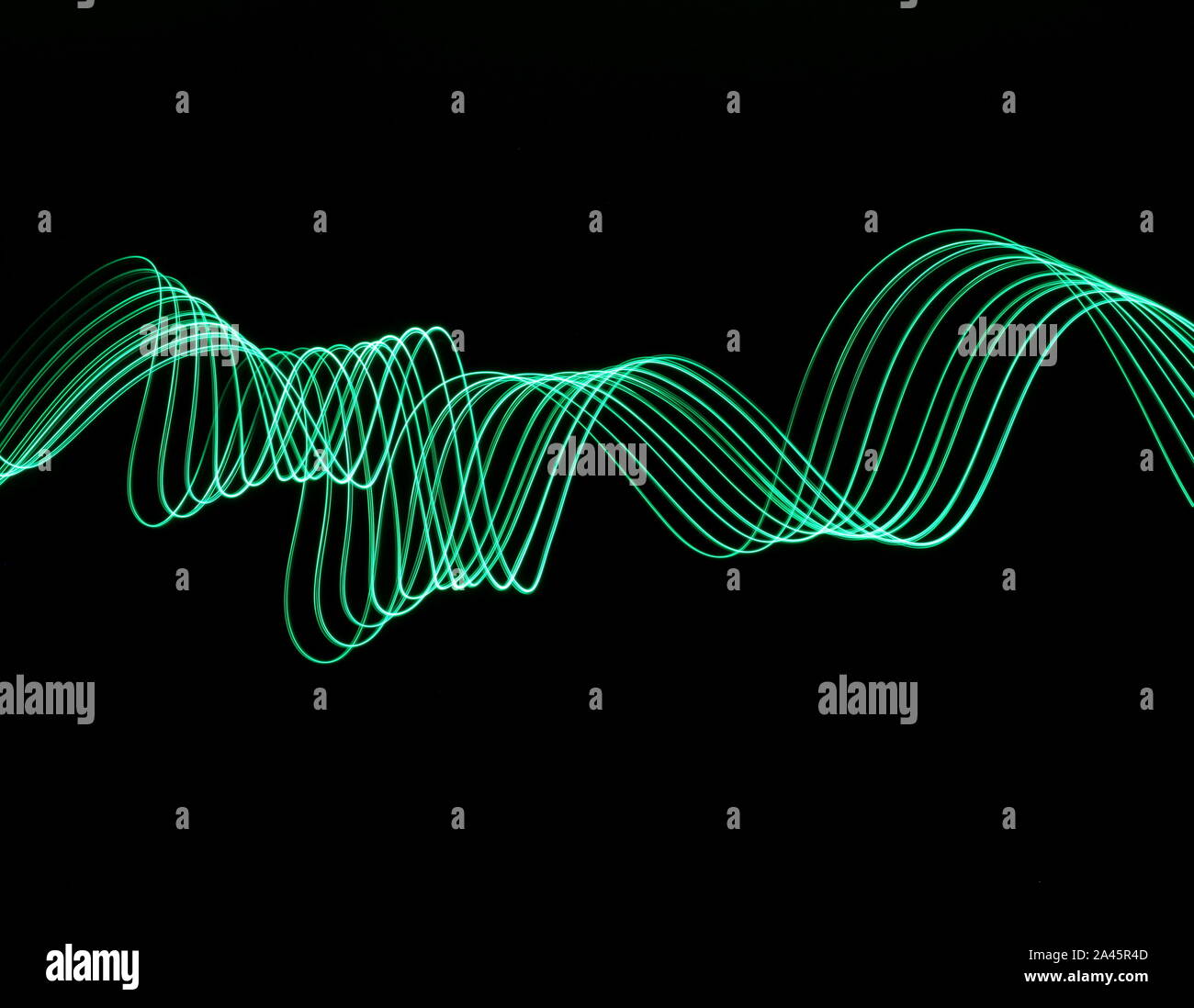 Une longue exposition photo de couleur vert néon dans un abrégé swirl, motif de lignes parallèles sur un fond noir. La lumière peinture photographie. Banque D'Images