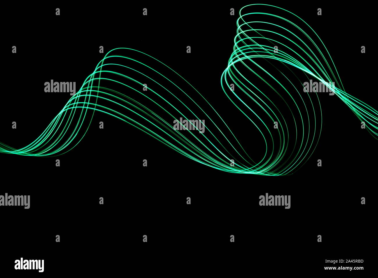 Une longue exposition photo de couleur vert néon dans un abrégé swirl, motif de lignes parallèles sur un fond noir. La lumière peinture photographie. Banque D'Images