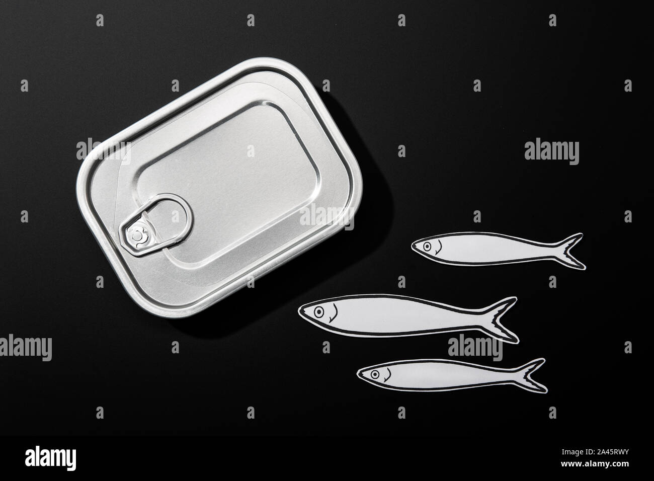 La conservation du poisson concept. Boite de conserve et du papier des sardines sur fond noir Banque D'Images