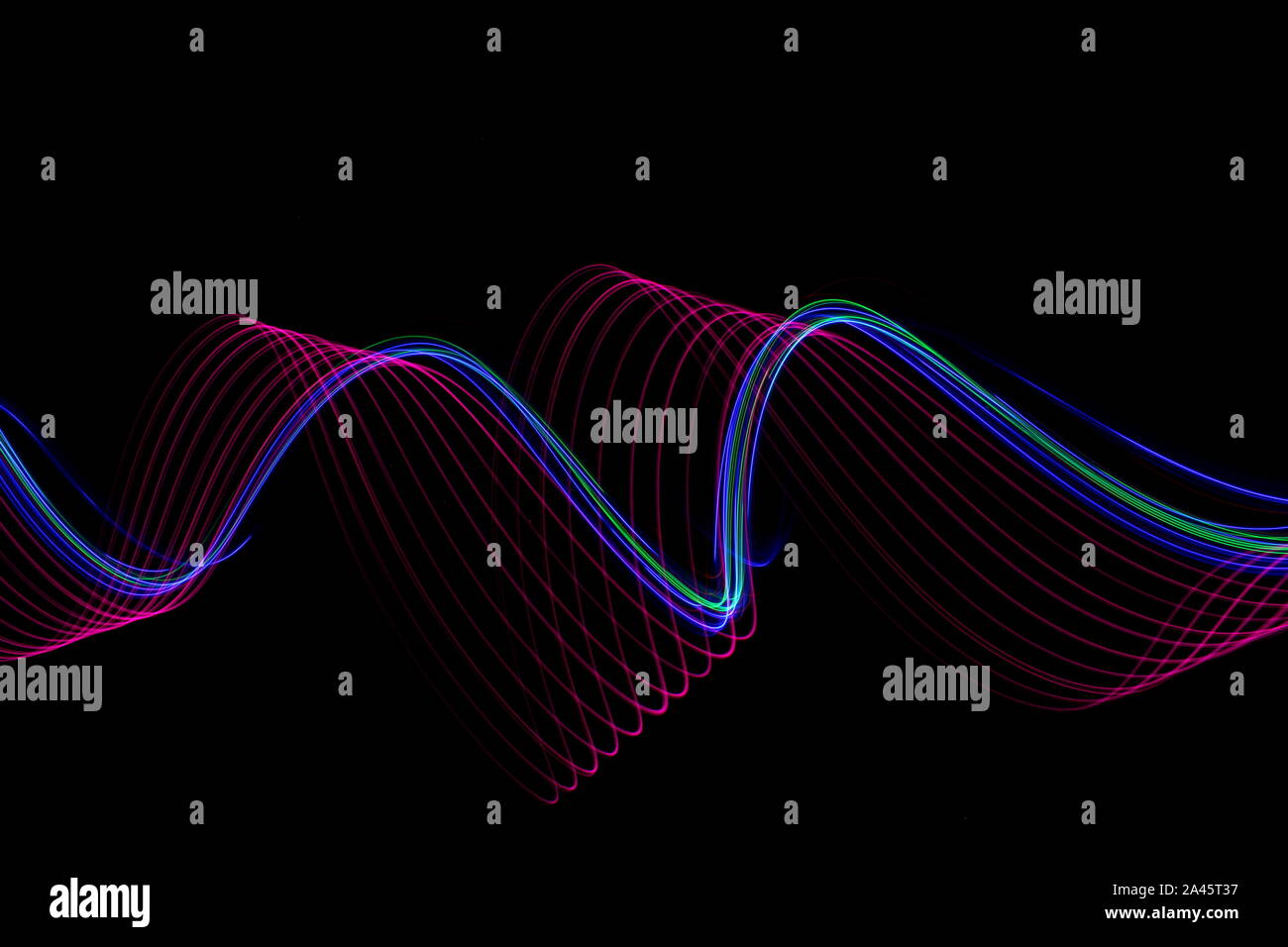 Une longue exposition photo de rose fluo et multi couleur dans un tourbillon abstrait, lignes parallèles sur un fond noir. La lumière peinture photographie. Banque D'Images
