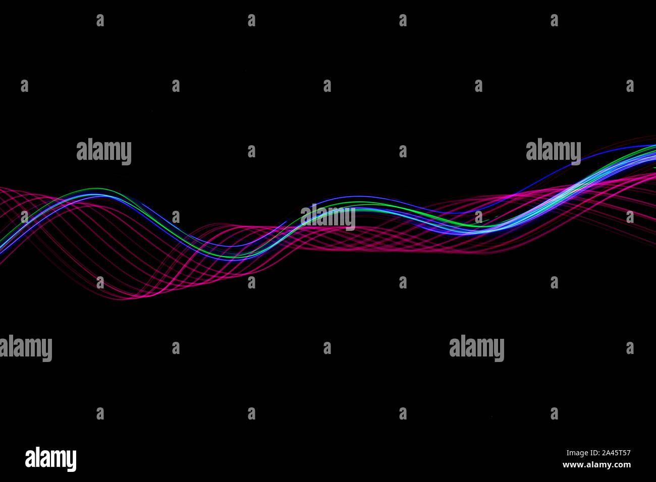 Une longue exposition photo de rose fluo et multi couleur dans un tourbillon abstrait, lignes parallèles sur un fond noir. La lumière peinture photographie. Banque D'Images