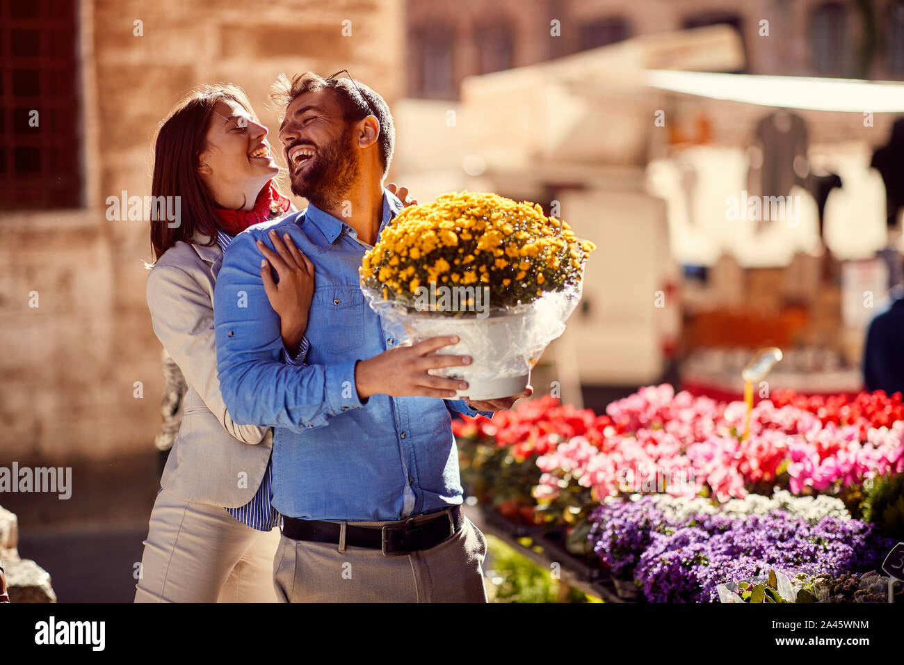 Heureux l'homme et de la femme shopping pour les plantes à fleurs sur la rue. Banque D'Images