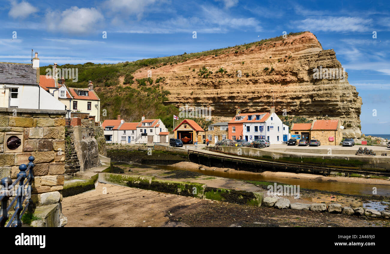 Falaise rouge des strates du Jurassique à l'embouchure de Staithes Beck se jette dans la mer du Nord à Staithes Harbour North York Moors National Park en Angleterre Banque D'Images