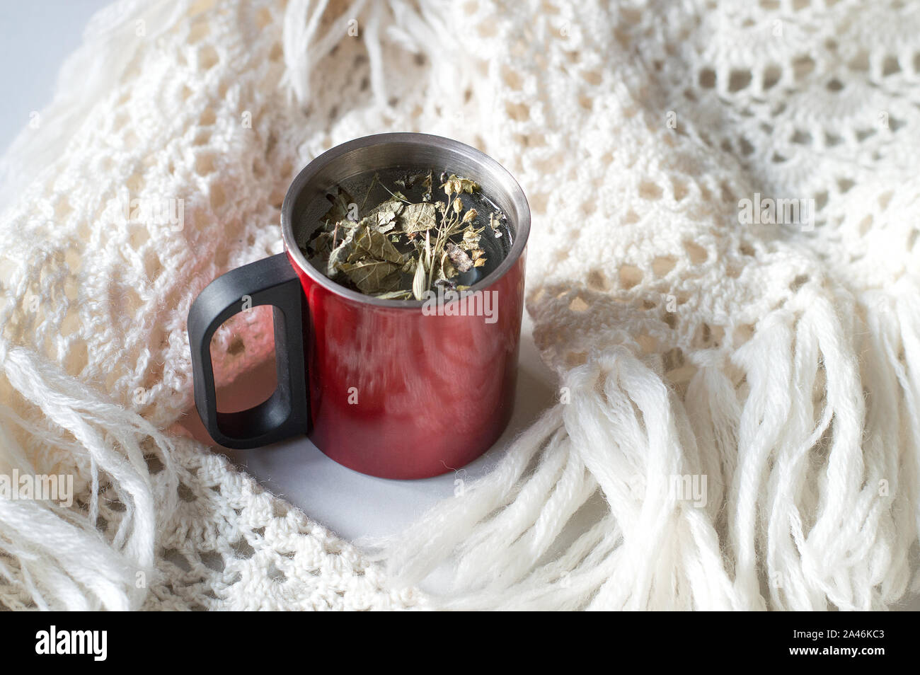 Une tasse de tisane dans la chaleur rouge à côté de la cuvette contenant chaud fanchon en bonneterie. Concept par temps froid. Le temps de Noël. Selective focus Banque D'Images