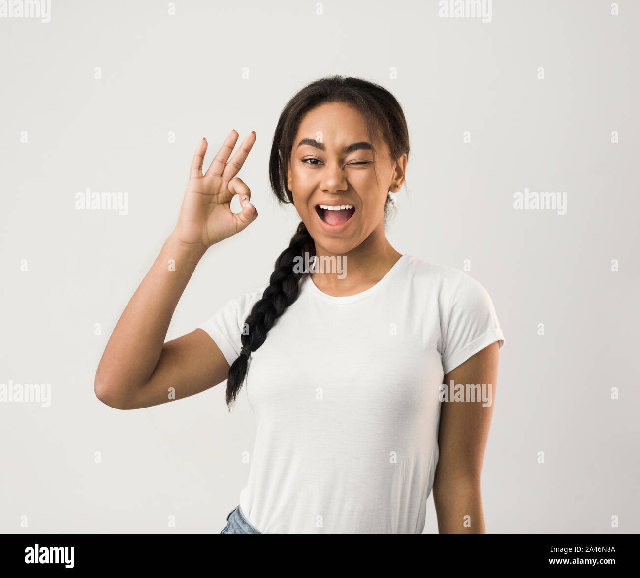 Happy girl gesturing OK sign et clignant de l'oeil Banque D'Images