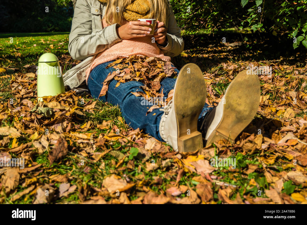 Jeune femme à boire le thé dans le parc en automne Banque D'Images
