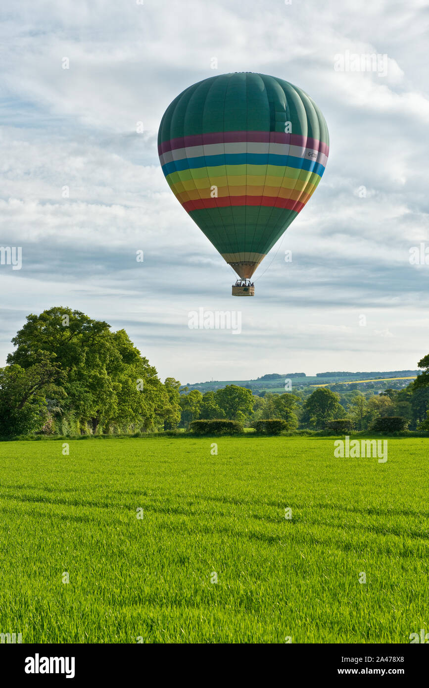 Hot Air Balloon volant à basse altitude au-dessus des champs cultivés. Midlothian, Ecosse Banque D'Images