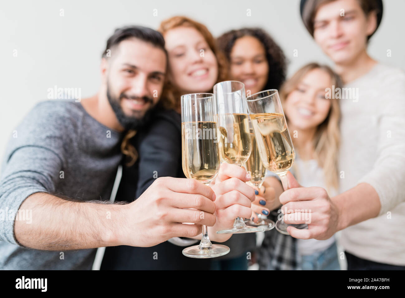 Plusieurs flûtes à champagne tenue par groupe de jeunes amis joyeux Banque D'Images
