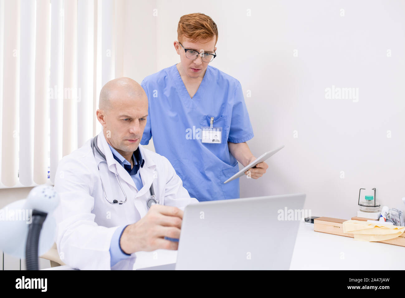Confiant mature doctor pointing at laptop Présentation affichage Banque D'Images