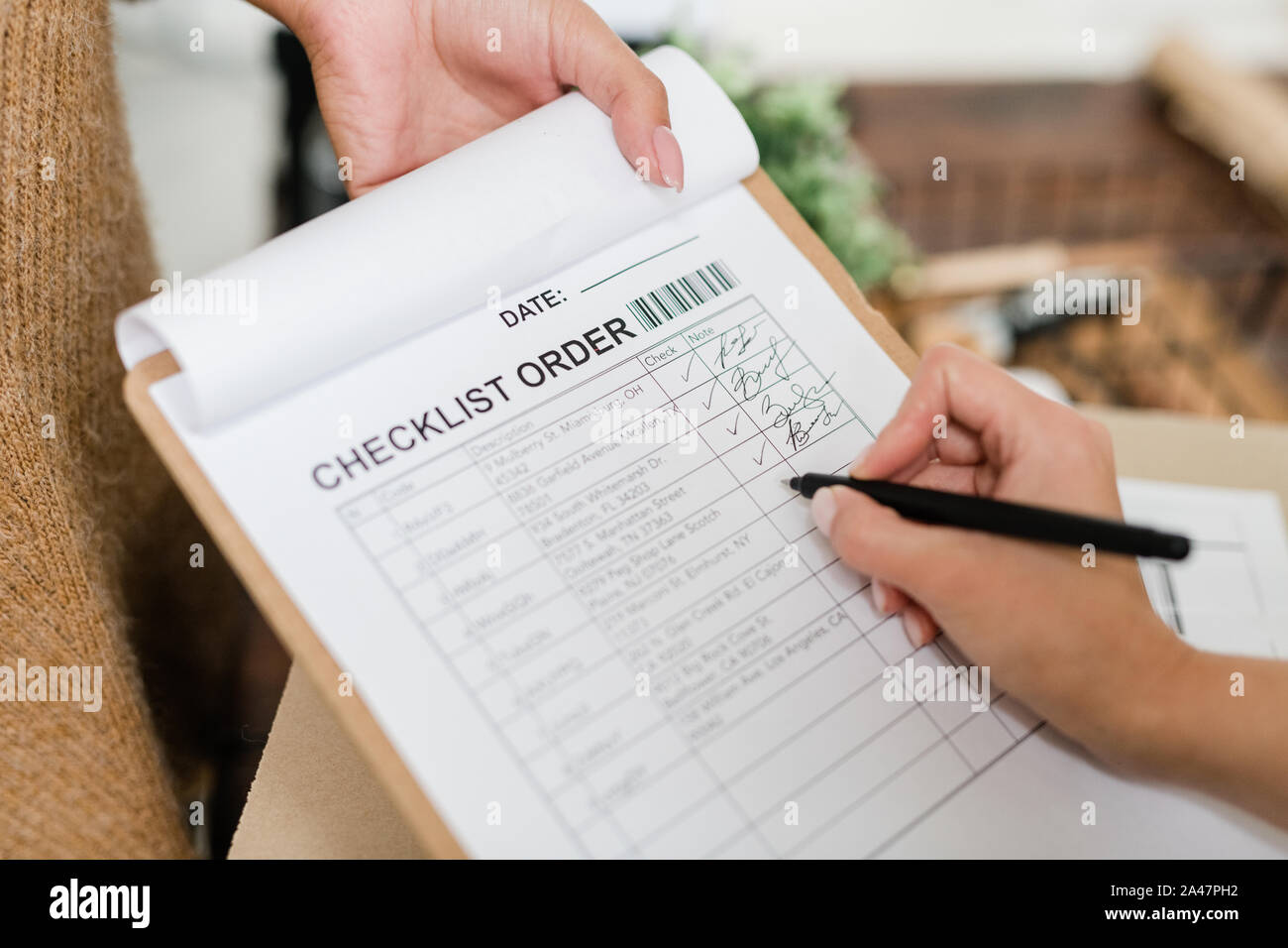 Femme avec un stylo va mettre cocher en face de l'un des articles commandés dans la liste de contrôle Banque D'Images