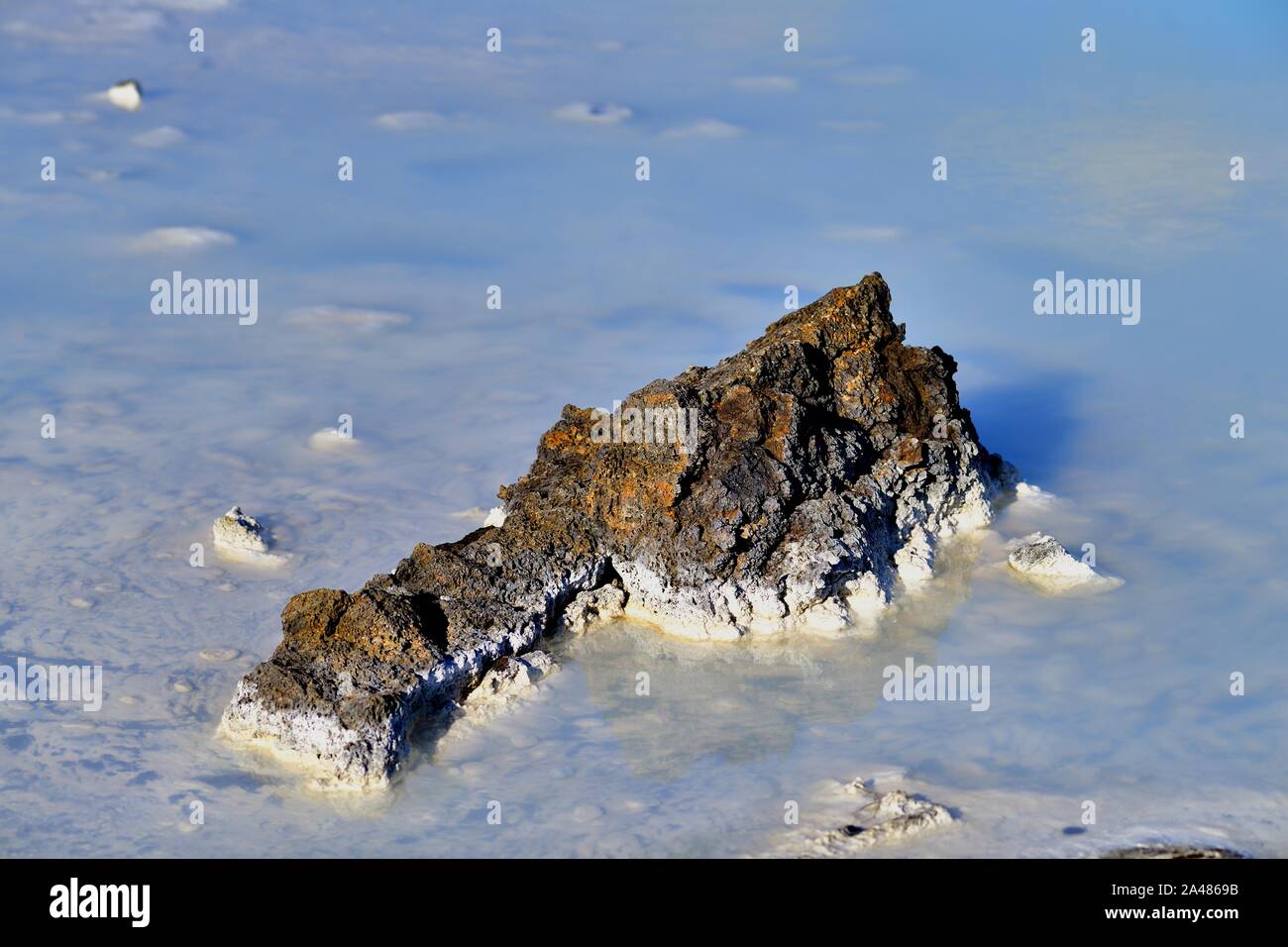 Svartsengi, Islande. Une formation rocheuse et dépôt minéral au milieu de l'eau très bleue au Blue Lagoon l'un des principaux sites touristiques de l'Islande. Banque D'Images