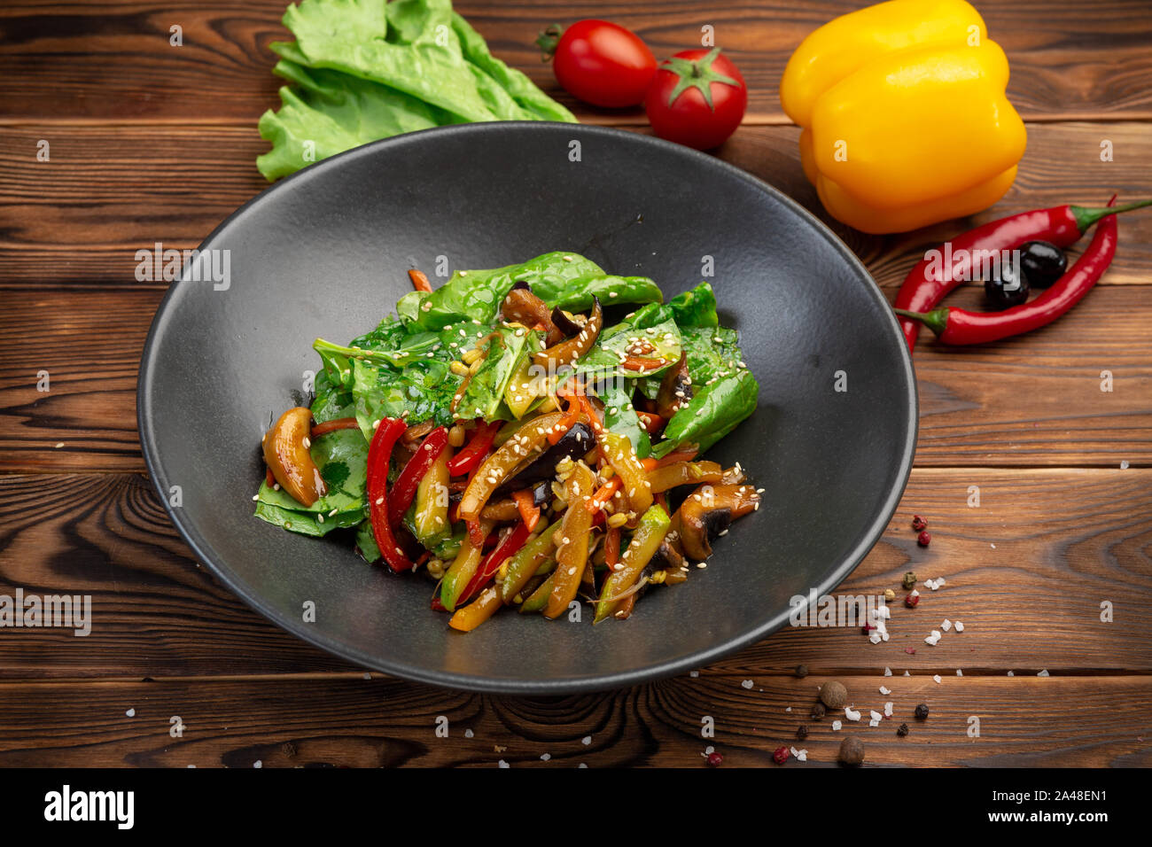 Wok de légumes frits : aubergines, carottes, champignons, courgettes,  oignons rouges, soja et pousses d'épinards frits dans la sauce teriyaki  dans une plaque noire sur un Photo Stock - Alamy