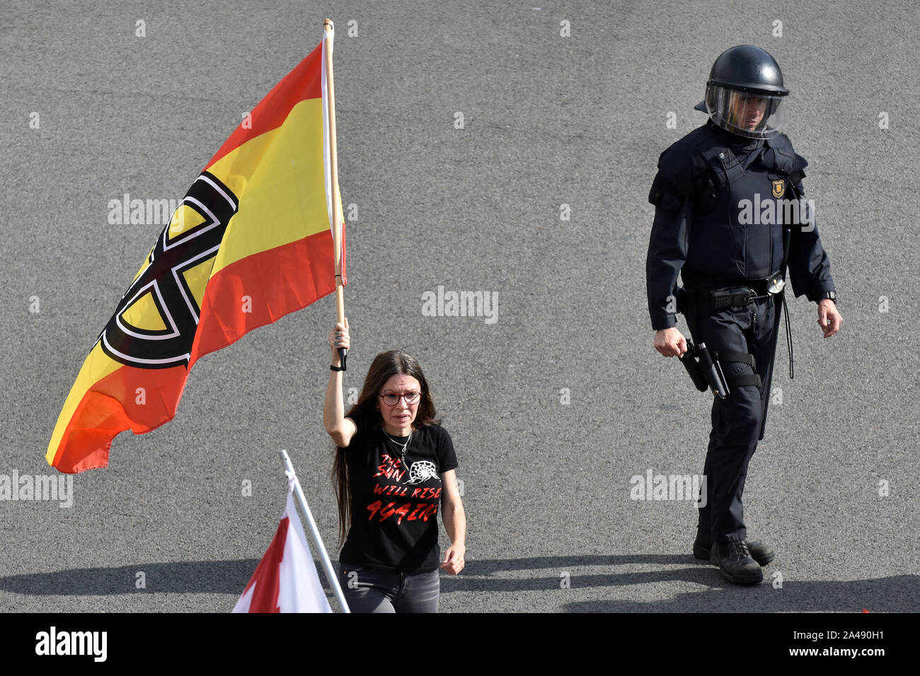 Barcelone, Espagne. 12 octobre, 2019. Un agent de police anti-émeute Catalan observe un manifestant avec un pavillon de l'Espagne avec des symboles liés au nazisme pendant la manifestation.Quelque 200 personnes de différents groupes liés à l'extrême droite ont manifesté pour l'unité de l'Espagne et contre l'indépendance de la Catalogne sur l'héritage hispanique à Barcelone. Credit : SOPA/Alamy Images Limited Live News Banque D'Images