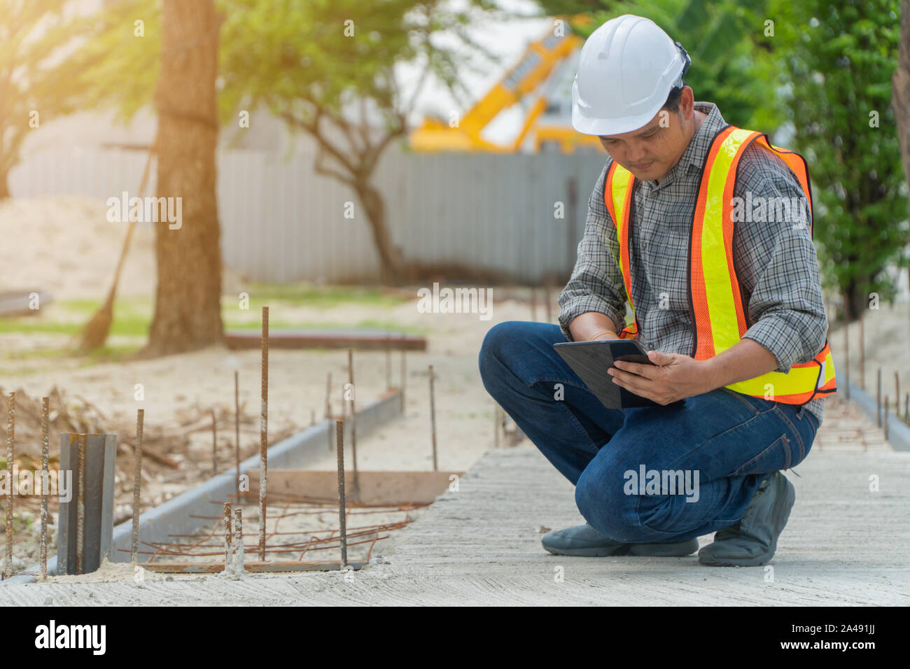 L'ingénierie, portant un casque et holding tablets, s'assoir pour vérifier la structure du couloir dans le parc Banque D'Images
