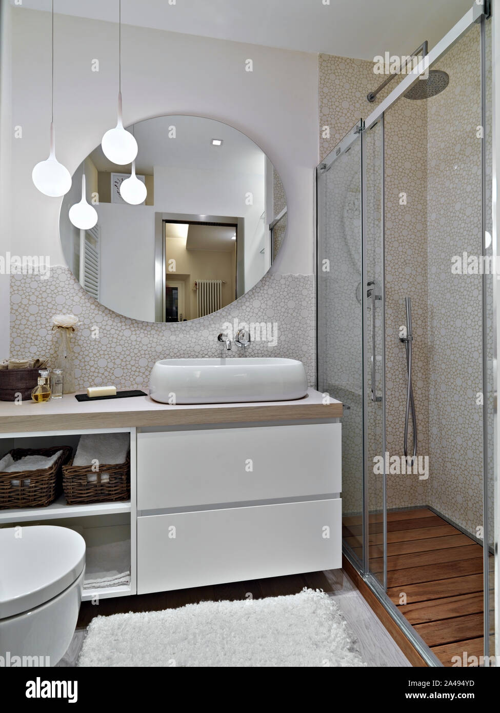 Tourné de l'intérieur d'une salle de bains moderne à l'avant-plan de  l'évier armoire avec un lavabo de comptoir et le grand miroir rond près de  cabine de douche Photo Stock - Alamy