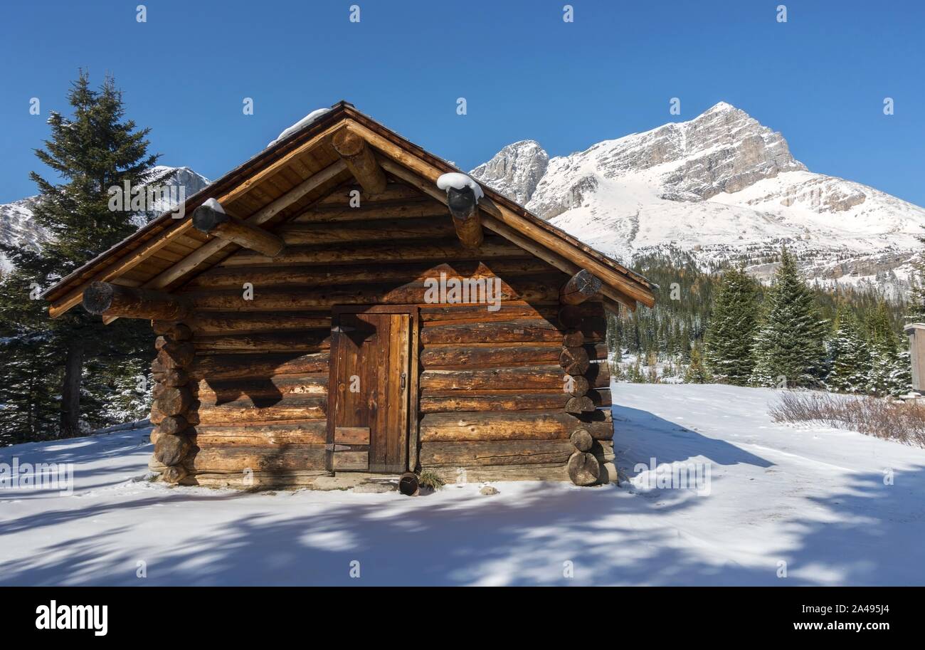Ancienne cabane en bois en rondins et ciel enneigé de Rocky Mountain Peak. Parc national Banff, Paysage panoramique d'hiver des Rocheuses canadiennes Banque D'Images