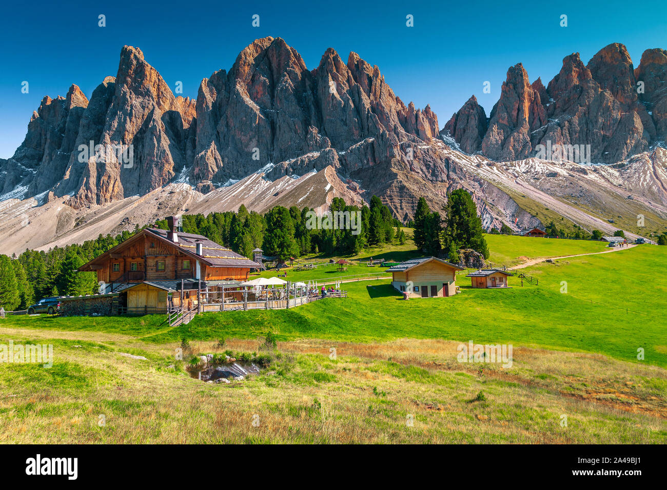 Paysage alpin printemps pittoresque touristique, chalets de montagne et un petit lac avec des hautes montagnes enneigées en arrière-plan, Odle Geisler - Groupe de montagne, Banque D'Images