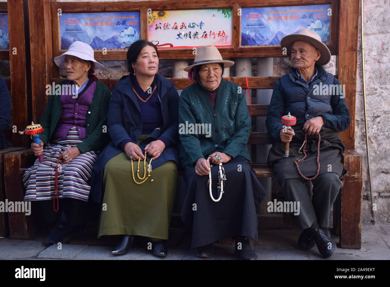 Quatre vieux tibétains en vêtements traditionnels assis sur un banc à proximité du temple du Jokhang à Lhassa - Tibet Banque D'Images