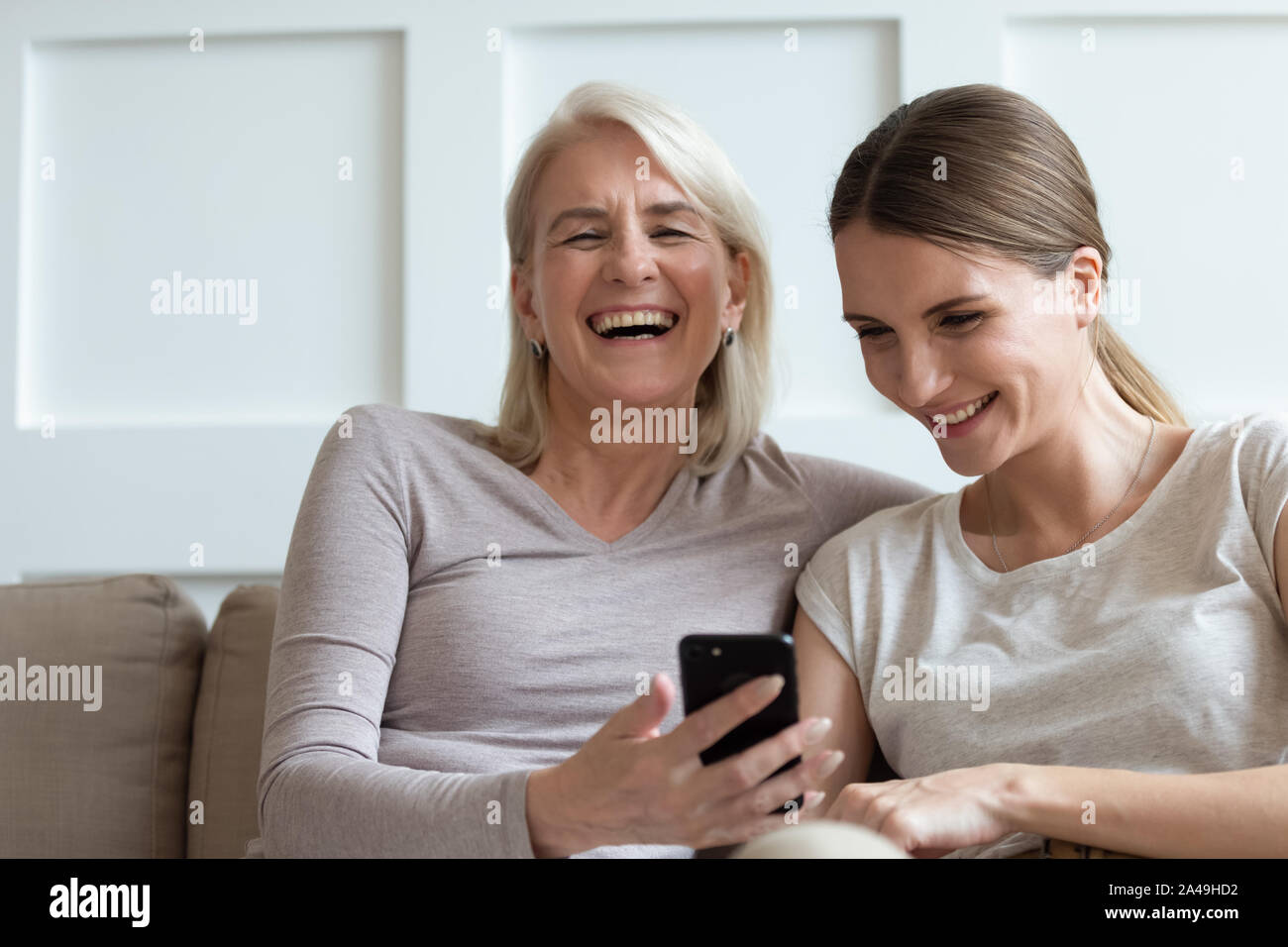 Mère et fille adultes regardant des vidéos drôles sur smartphone rire Banque D'Images