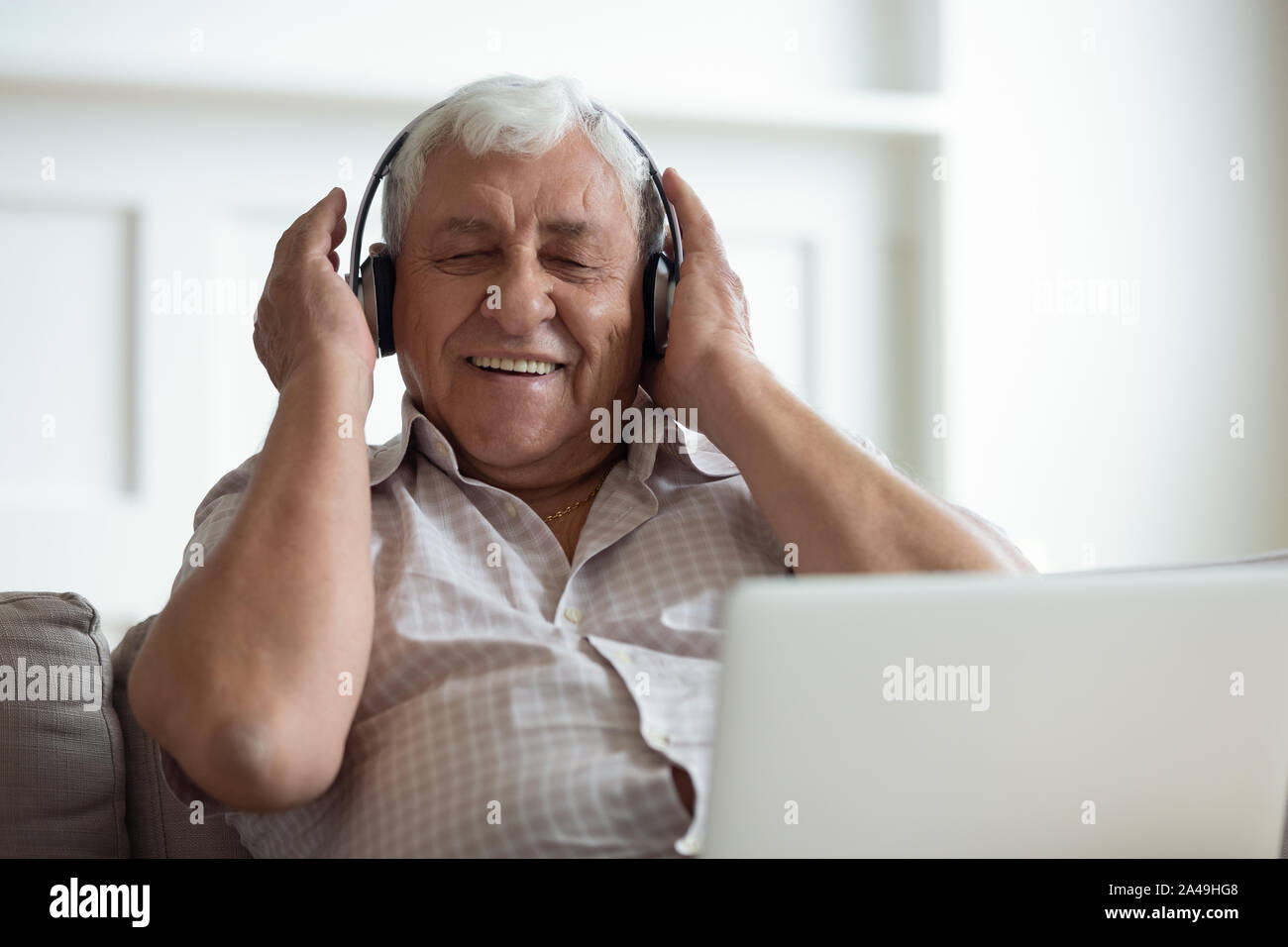 Senior man wearing headphones écoute des chansons sur ordinateur portable Banque D'Images