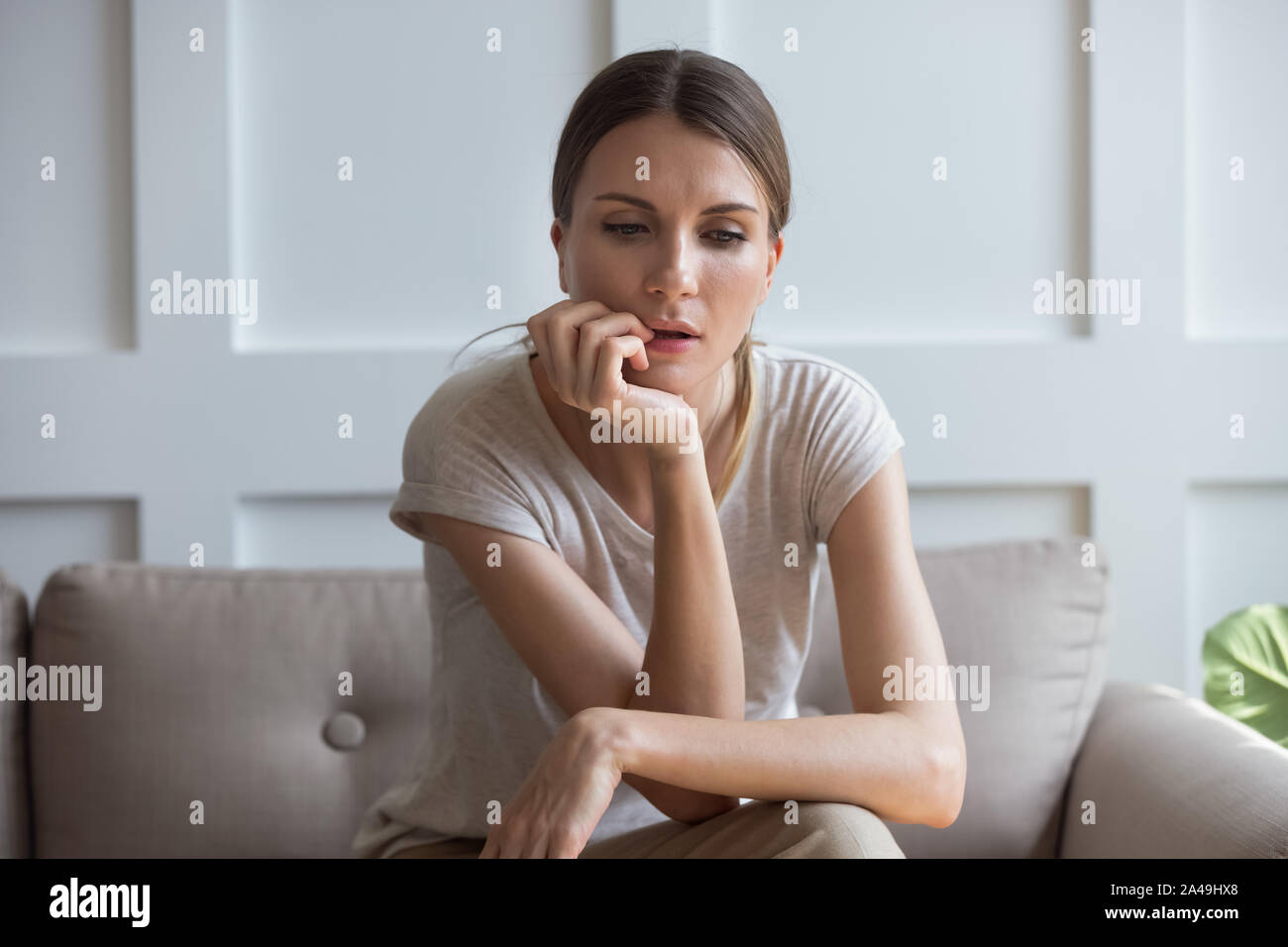 Perdu sur les tristes pensées woman sitting on sofa at home Banque D'Images