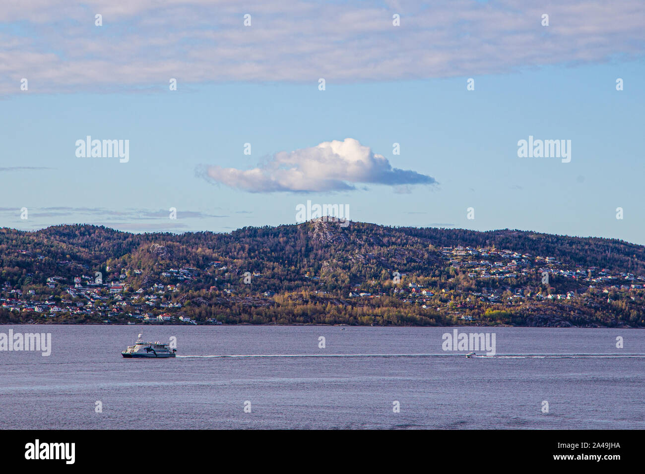 Bateaux dans port de Bergen, Bergen, Norvège. Un seul nuage dans le ciel au-dessus d'une montagne. Banque D'Images