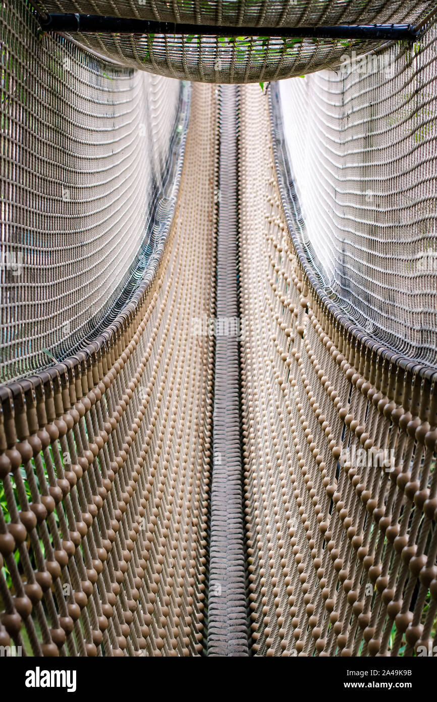 Corde suspendu pont étroit pour le divertissement, sur les côtés et le haut avec une grille pour la sécurité. Belle texture. Banque D'Images