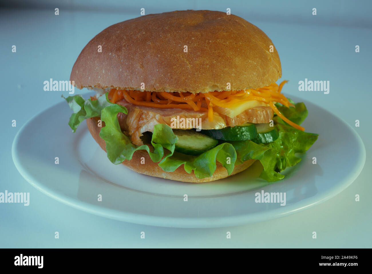 Un grand et savoureux avec un hamburger juteux morceau de poulet, concombres, carottes et coréen du fromage. Sur une plaque blanche Banque D'Images
