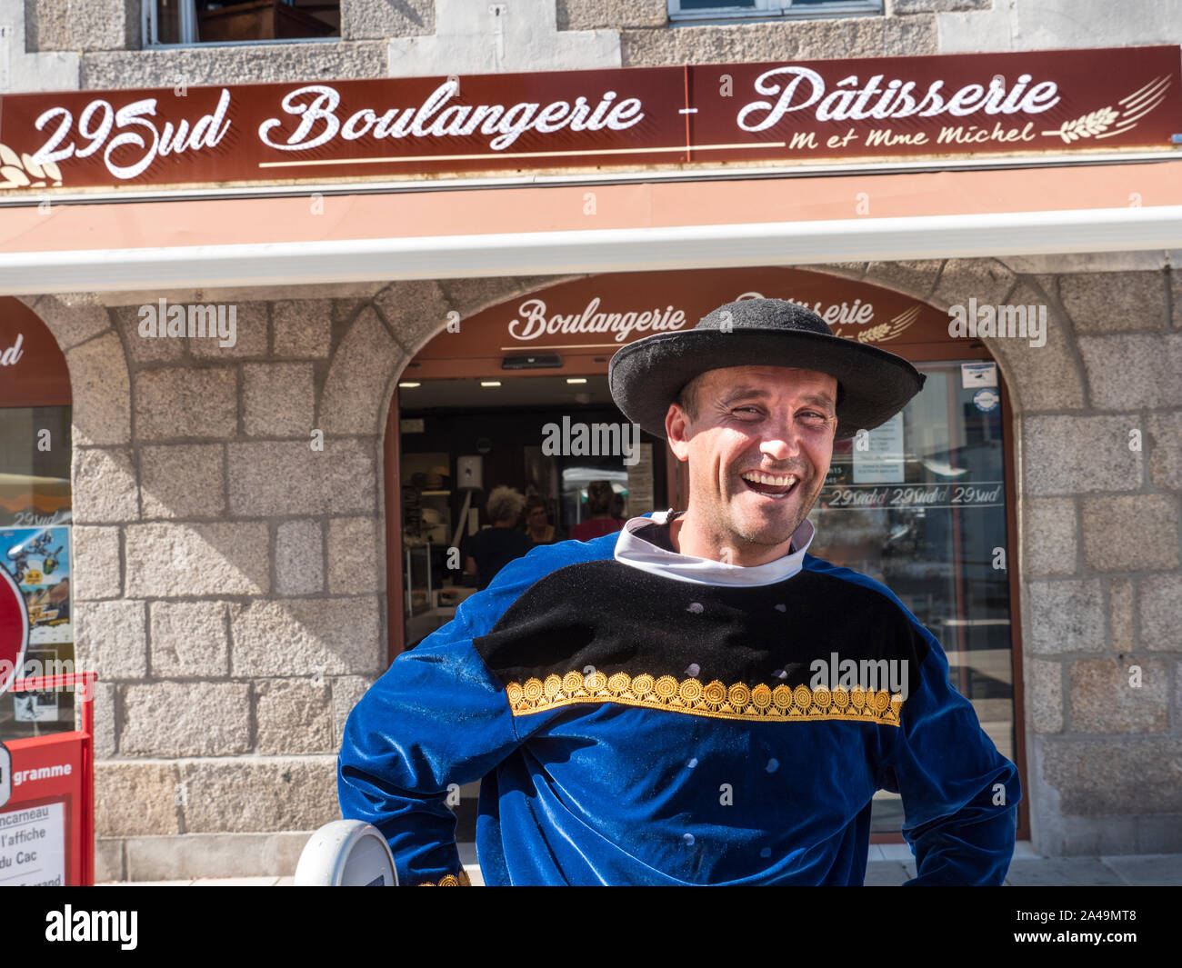 Marché de la rue Breton Névez heureux personnage français marché extérieur titulaire d'une robe traditionnelle bretonne à un marché hebdomadaire en riant à l'extérieur de la 29Sud Boulangerie-pâtisserie à Névez Bretagne France Banque D'Images