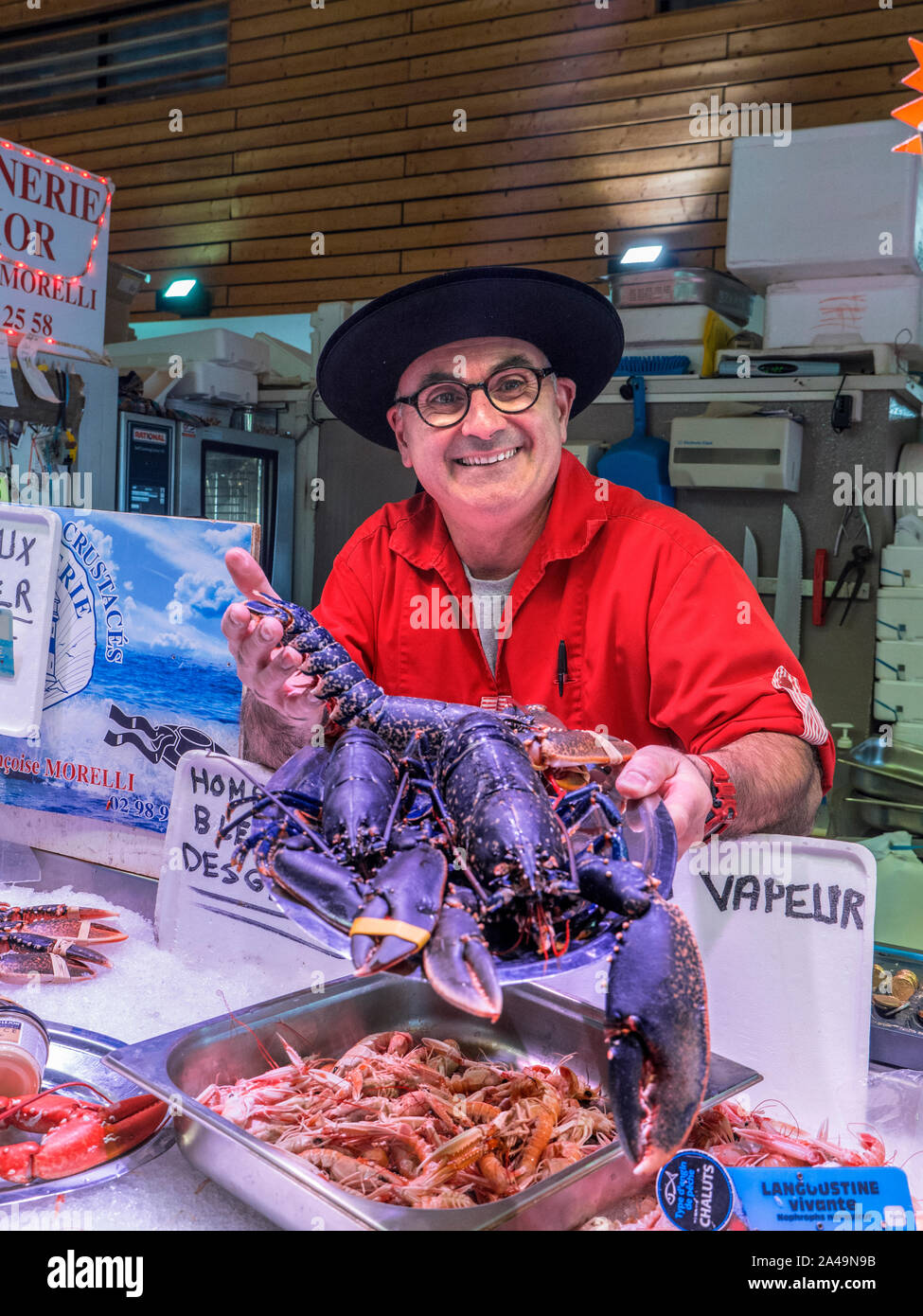 BRETON POISSONNIER & LIVE HOMARD BLEU CLEUNES FISH MARKET STALL CONCARNEAU FRANCE BRETAGNE Concarneau Marché aux poissons quotidien français de l'intérieur et de caractère hall poissonnier, dans le style Breton affichant fièrement son costume homard bleu live locale à vendre Bretagne Finistère France Banque D'Images
