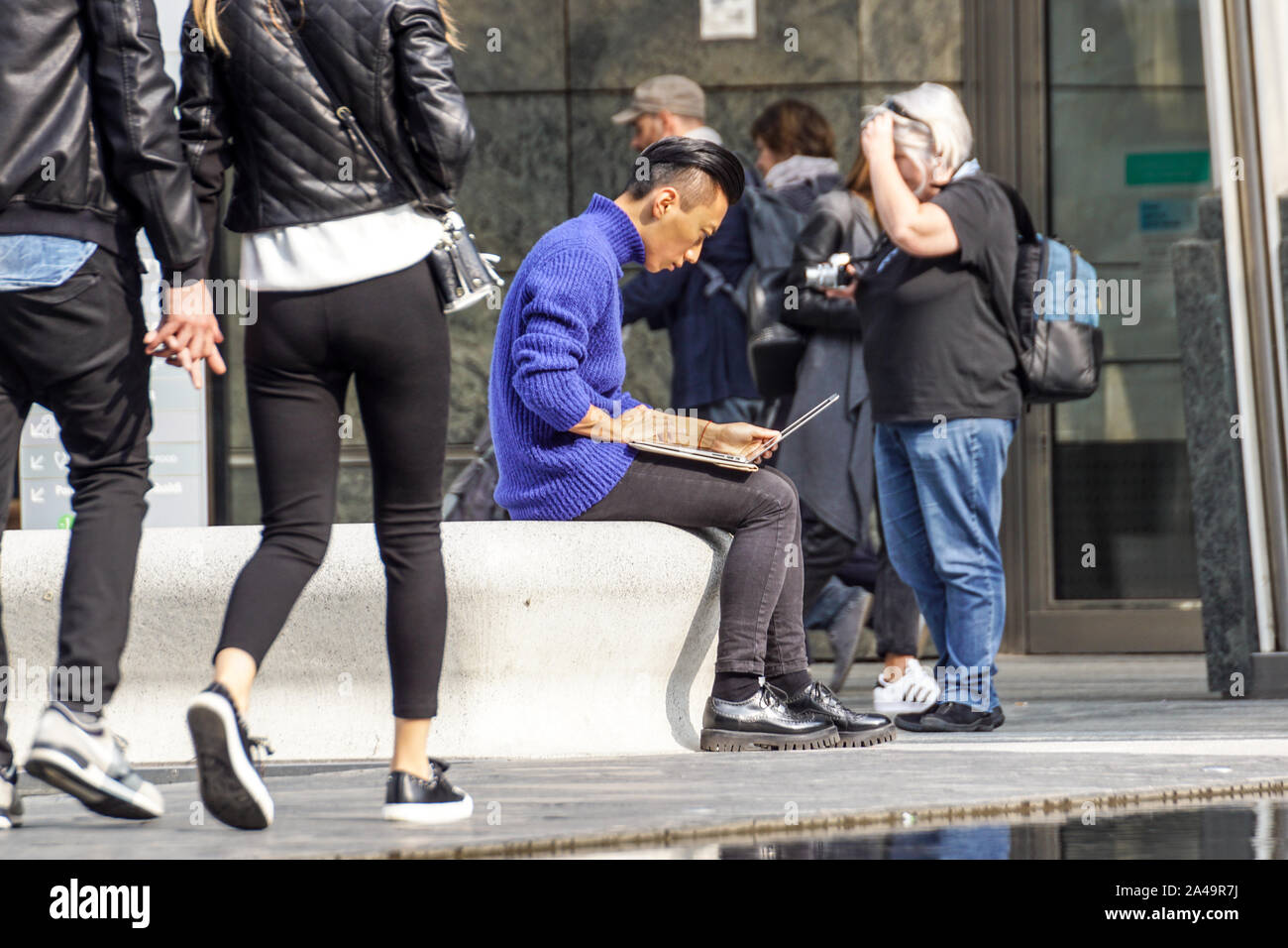 MILAN, ITALIE 4 MAI 2019 : Jeune homme à l'aide de PC pour travailler tout en étant assis sur le benchin le carré de la ville . Banque D'Images