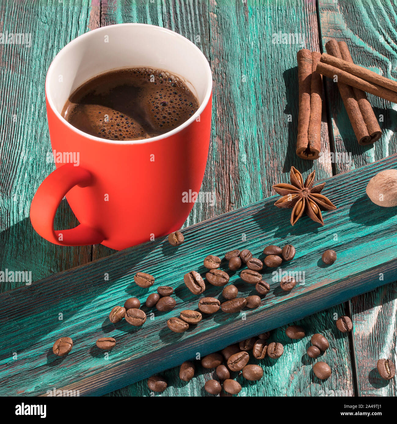 Une tasse de café fraîchement torréfié et de haricots sur une table en bois rustique. Matin ensoleillé. Coupe du corail lumineux sur fond bleu turquoise. Image carré Banque D'Images