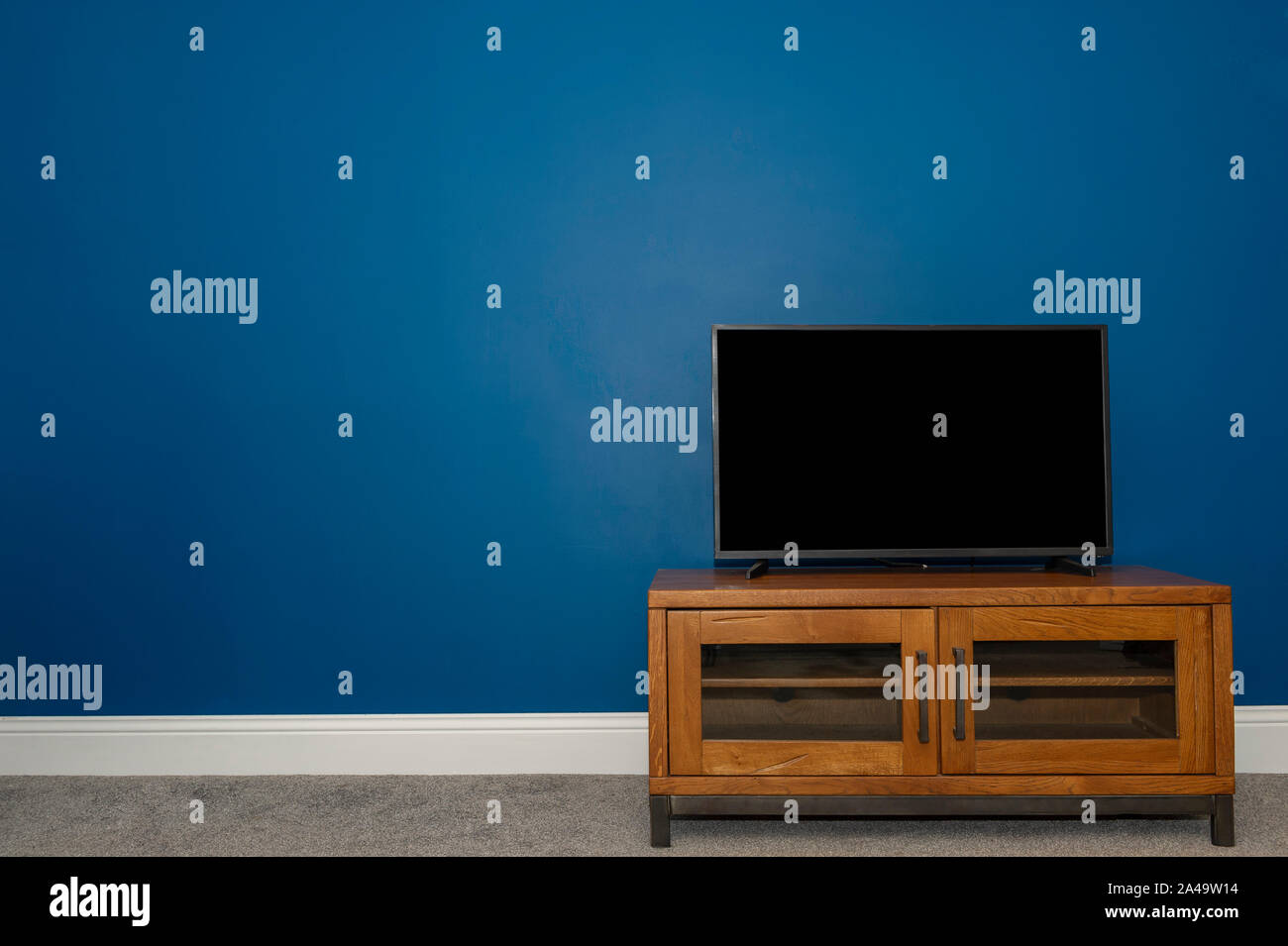 Un chêne industriel & Metal meuble TV et TV à écran plat contre un mur bleu Atlantique profonde Banque D'Images