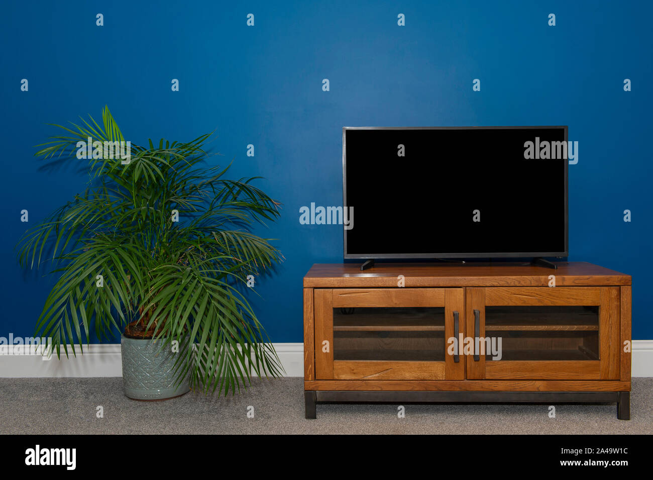 Un chêne industriel & Metal meuble TV et TV à écran plat contre un mur bleu Atlantique profonde Banque D'Images