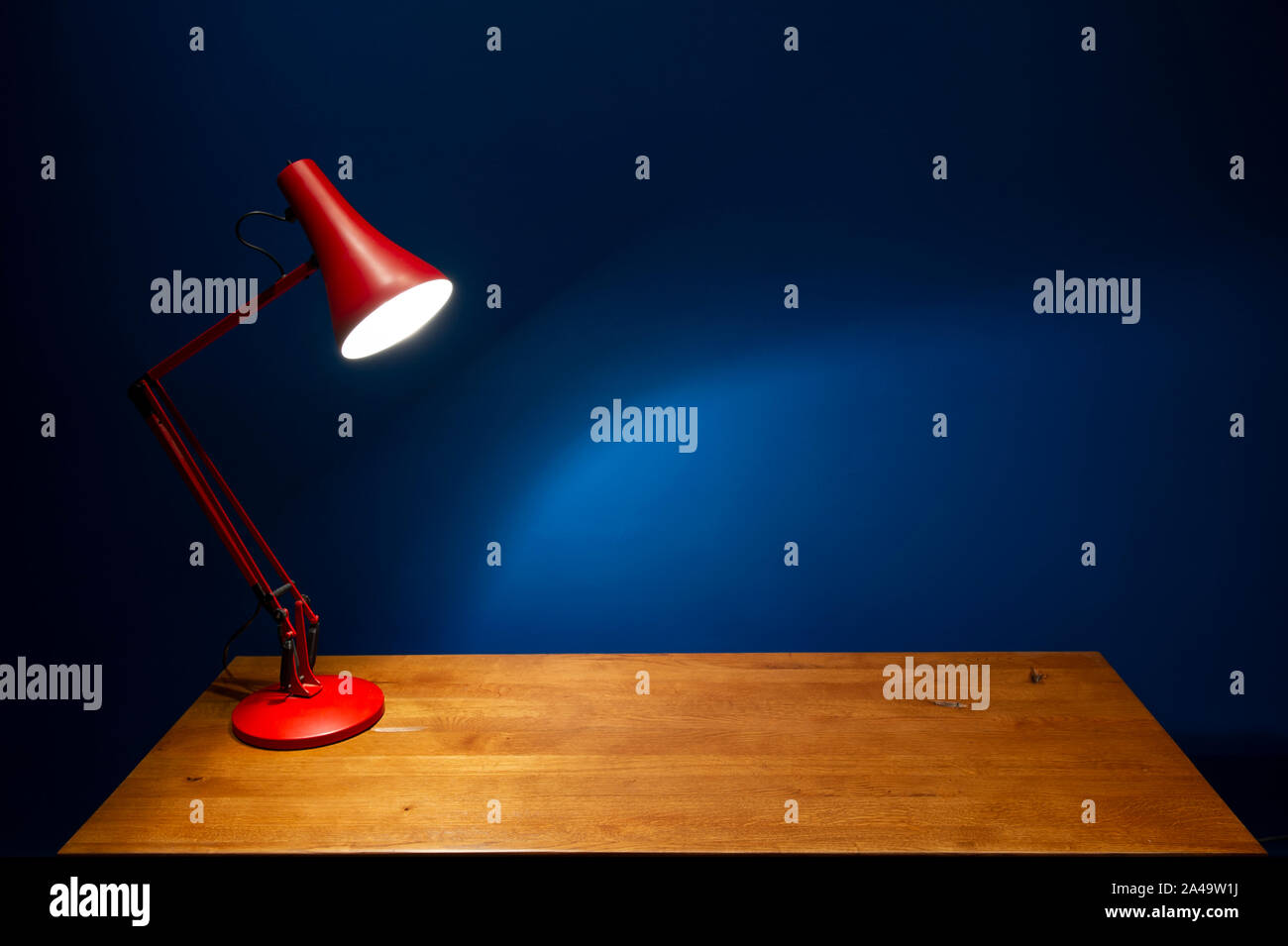 Un modèle de Terry Herbert Anglepoise Vintage Rouge 90 Lampe de bureau industrielle contre un mur bleu Atlantique profonde. Banque D'Images