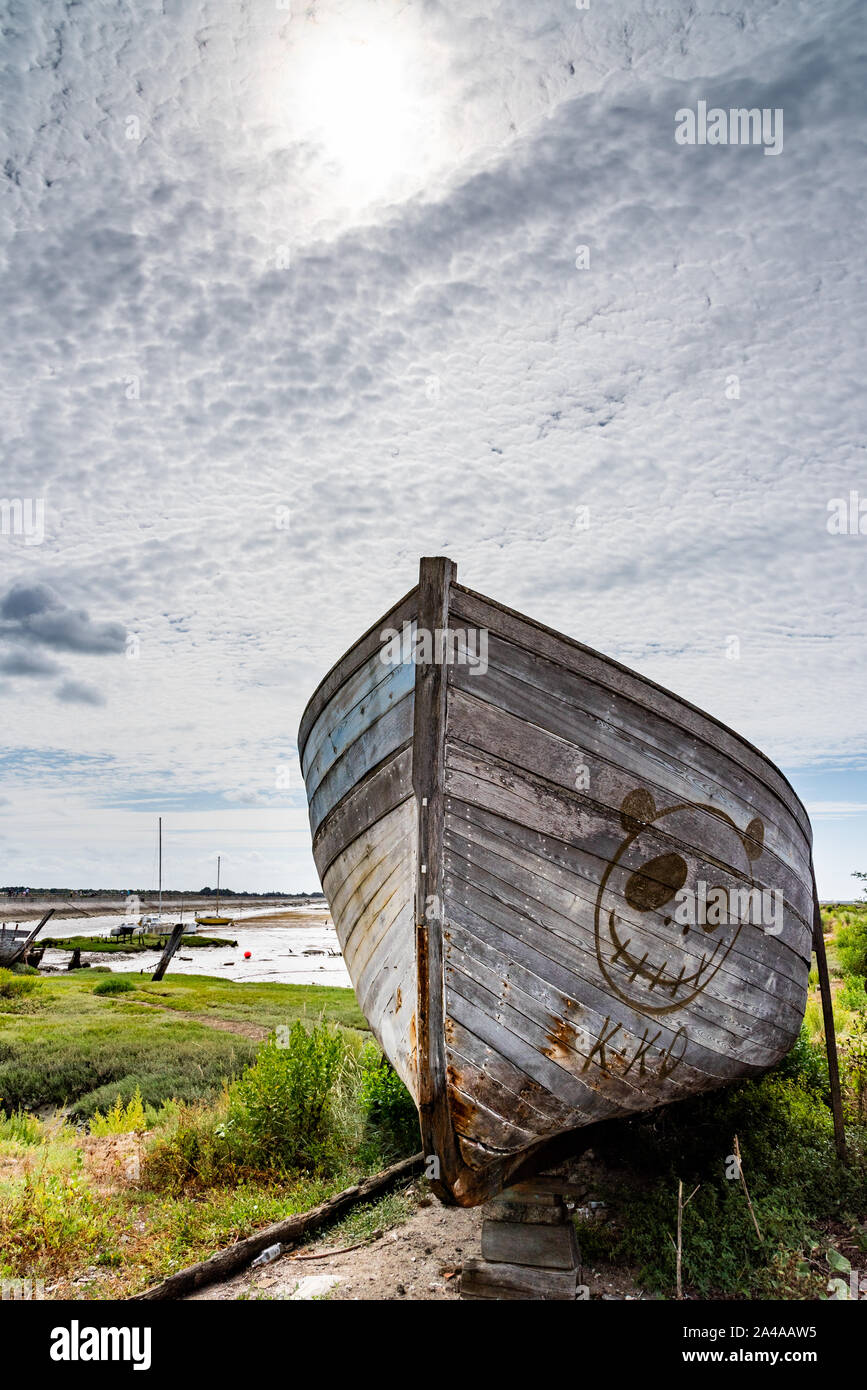 Le cimetière de bateaux de Noirmoutier. La proue de l'épave d'un vieux bateau de pêche en bois se tient sous un ciel nuageux Banque D'Images