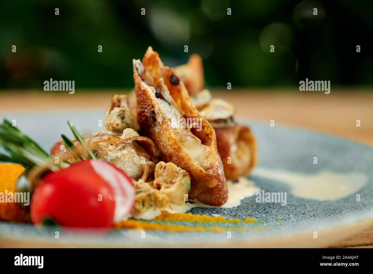 Délicieuses crêpes aux champignons et fromage, servi sur assiette bleue avec sauce blanche et la tomate. Banque D'Images