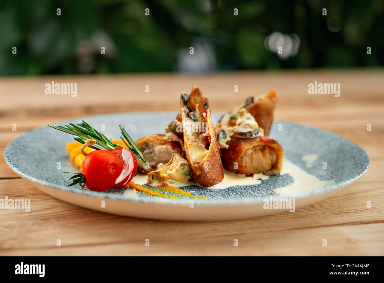 De délicieuses crêpes aux champignons et fromage, servi sur assiette bleue avec sauce blanche et la tomate. Banque D'Images